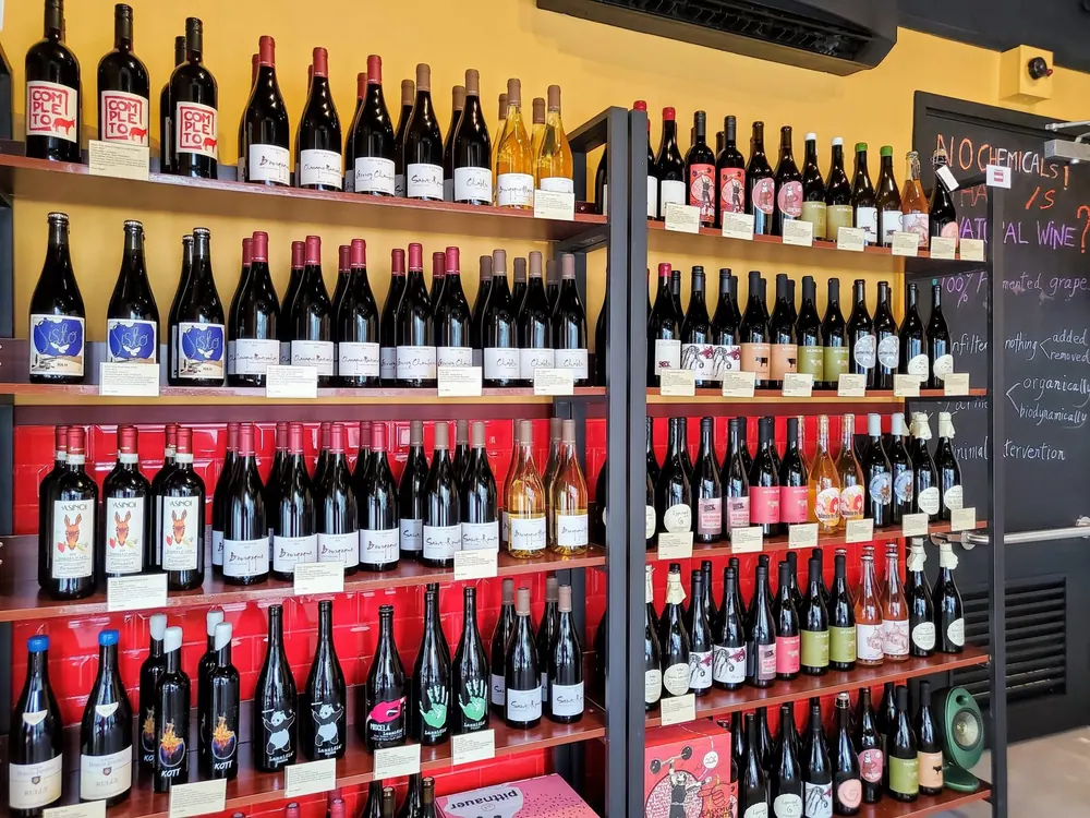 Shelves of natural wine against a red wall