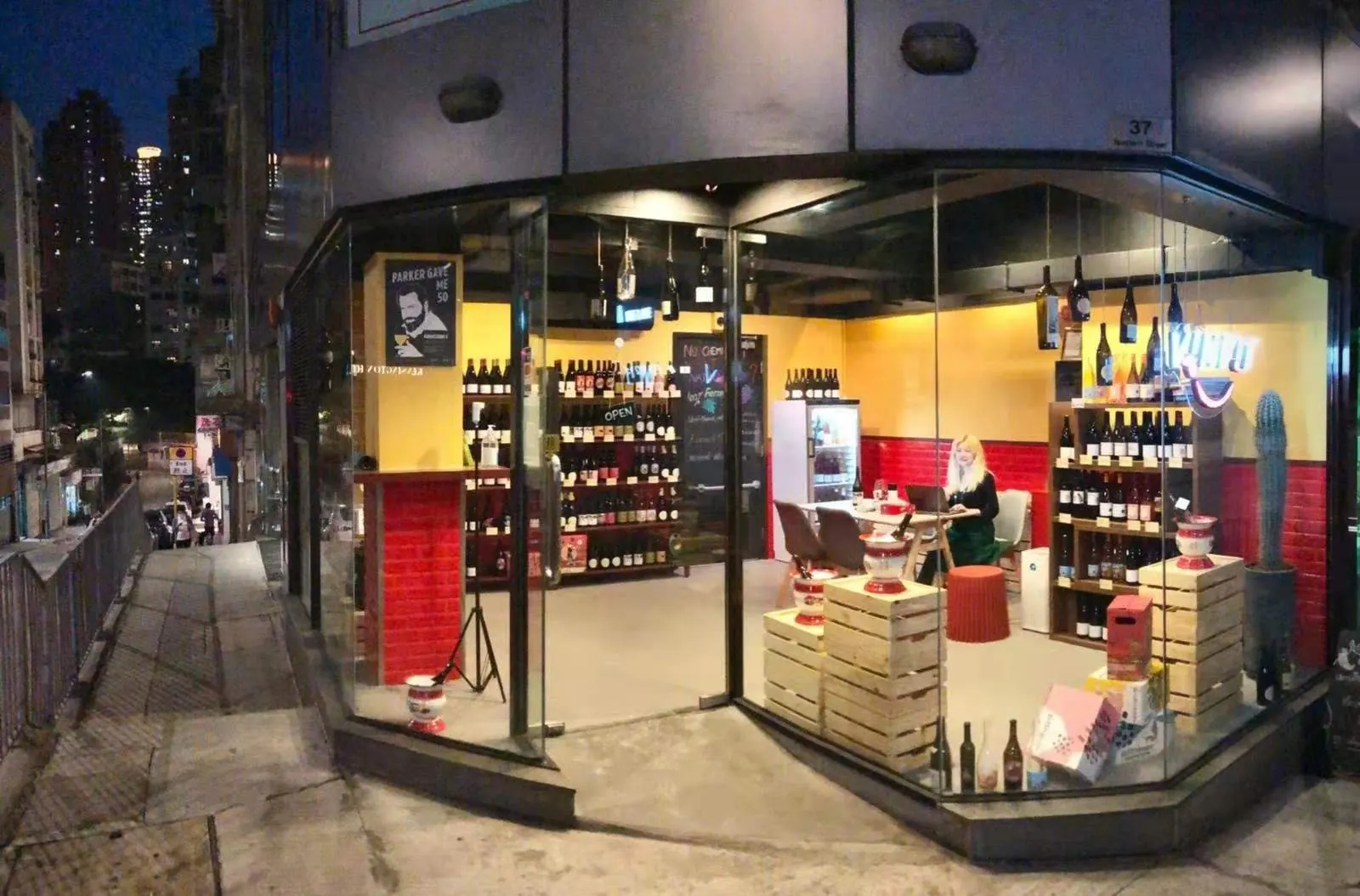The Vinpit shop front at night in Sai Ying Pun, its shelves of wine lit up behind the glass