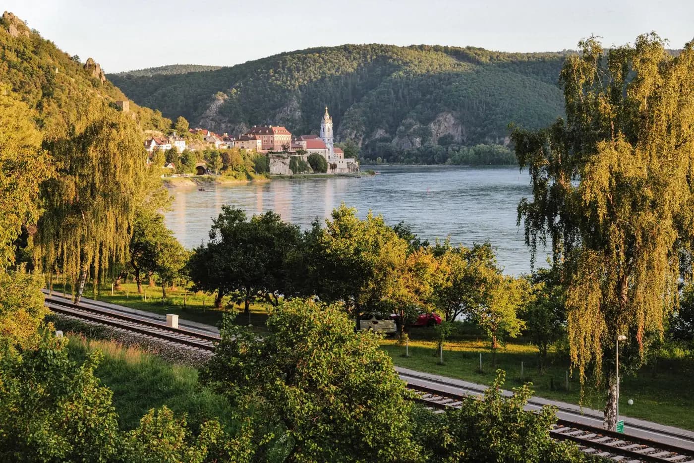 Autumn trees beside the Danube, with Dürnstein's church tower across the water